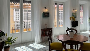 A dining area with a round wooden table, yellow chairs, and a potted plant.