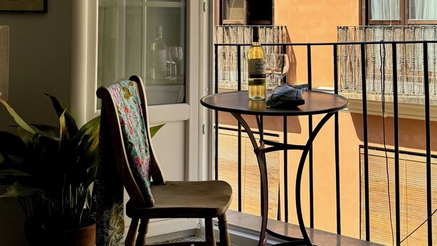 A balcony with a chair, a table, and a potted plant.