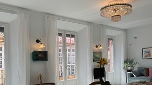 A dining area with a round wooden table, yellow upholstered chairs, and a chandelier.