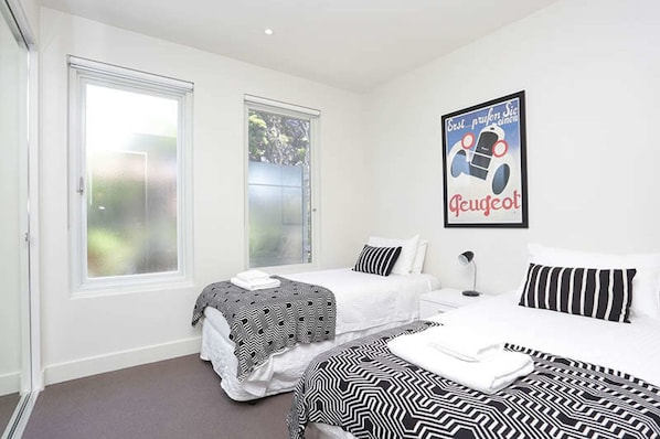A bedroom with two beds, a large window, and a poster on the wall.