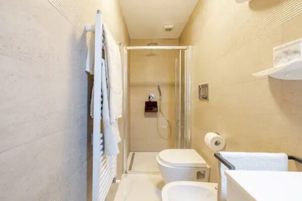 A compact bathroom with a glass shower enclosure, a toilet, and a sink.