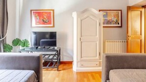 Une chambre d’hôtel comprenant un lit, un bureau avec un ordinateur, une armoire et deux œuvres d’art encadrées accrochées au mur.