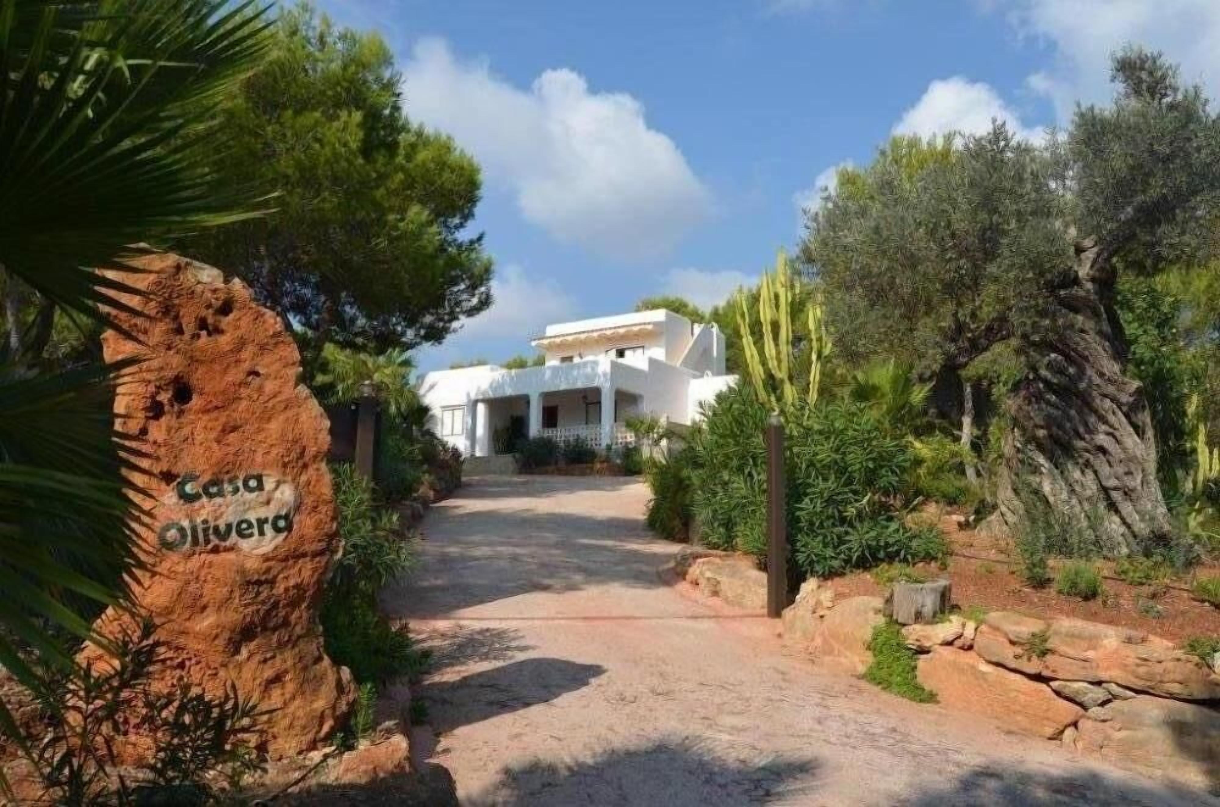 Un sendero que conduce a un edificio blanco con un letrero que dice 'Casa Olivera'.