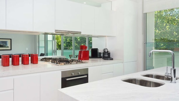 Una cucina moderna con mobili bianchi, piano cottura a gas, macchina da caffè e lavastoviglie.