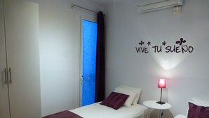 A bedroom with two beds, a bedside table with a lamp, a wardrobe, and a wall with a motivational quote. - New apartment, 6 pers, free WiFi, Sagrada Familia (Barcelona)