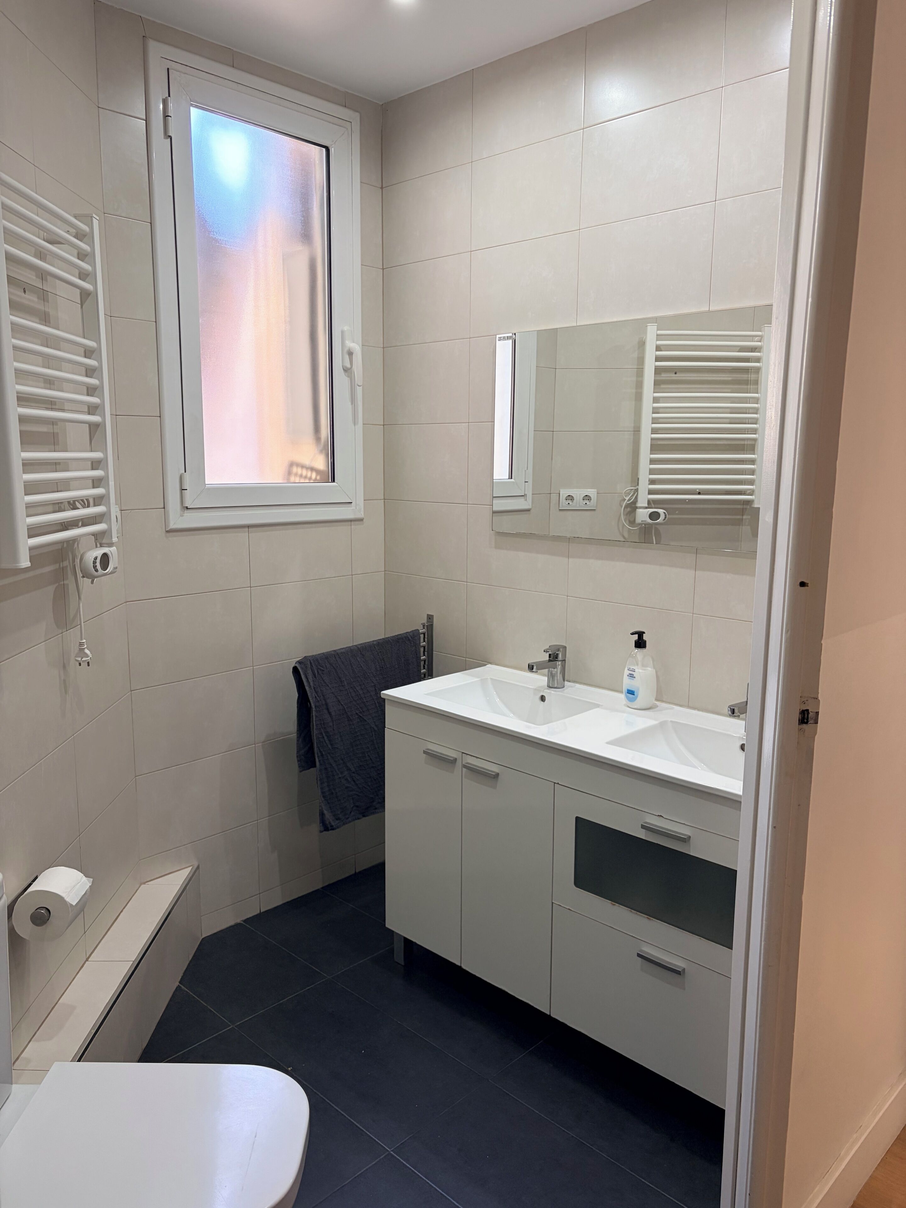 A modern bathroom with a white sink, mirror, and towel rack.