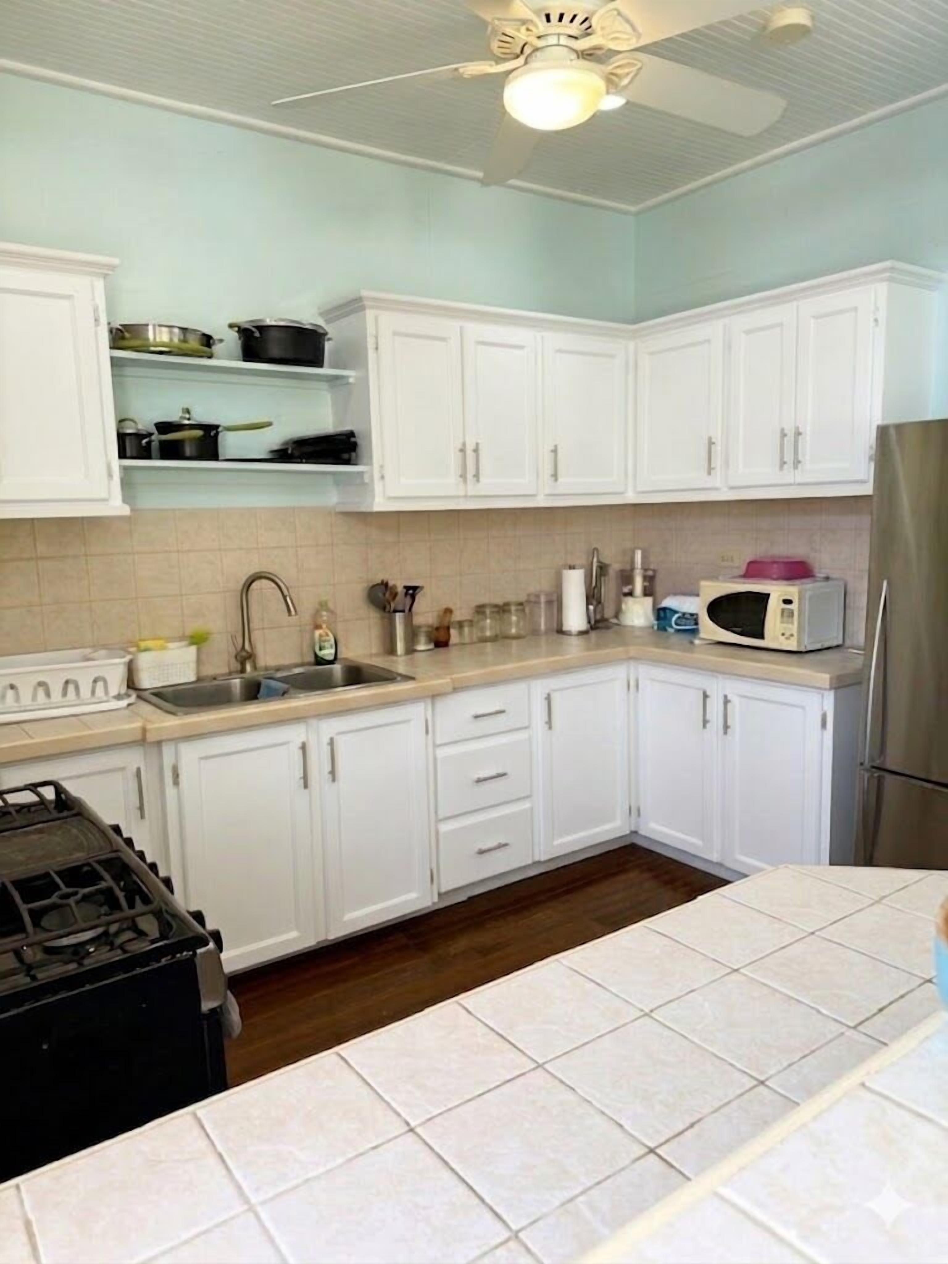 A kitchen with white cabinets, a microwave, a refrigerator, and a gas stove.