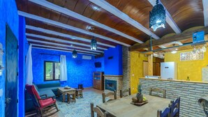 A dining area with a wooden table and chairs, a blue wall, and a fireplace.