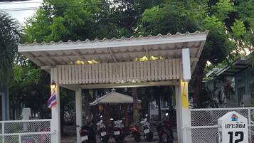 A covered parking area with several motorcycles parked under a white canopy. A sign with the number 12 is visible to the right.