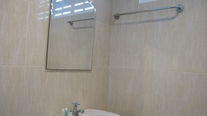 Un baño con lavamanos blanco, un espejo y un perchero para toallas.