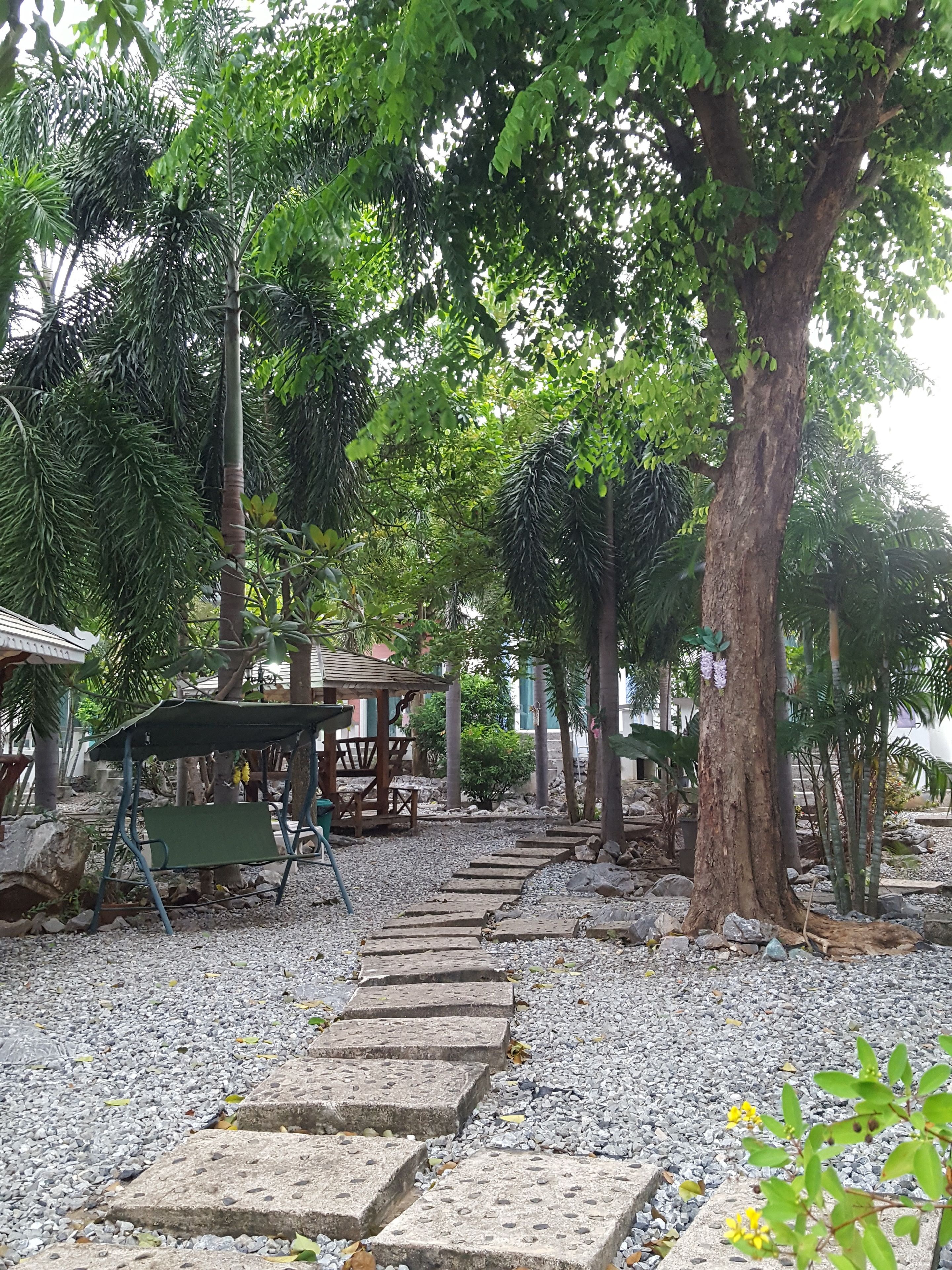 Un jardín con un sendero, bancos y un pabellón.