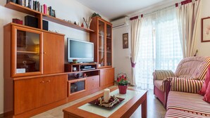 A living room with a television, wooden cabinets, a sofa, and a coffee table.