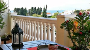 A balcony with a table, a potted plant, a lantern, and a decorative bowl.
