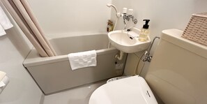 A bathroom with a bathtub, a sink, and a toilet. - Pension Sunset Beach (Nakijin)