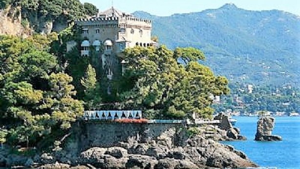 Un bâtiment qui ressemble à un château, situé sur une île rocheuse entourée d’eau.