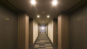 A hotel corridor with checkered carpet, doors numbered 337 and 321, and recessed lighting.