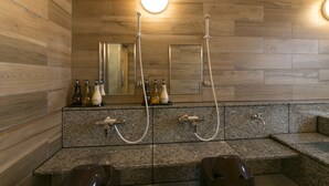 A modern bathroom with wooden paneling, granite countertops, and a large mirror.