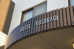 A hotel sign with the name "HOTEL KOSANAGI" in a modern, metallic font.