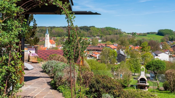 A stone pathway leading to a covered area with a view of a village and a church. - Apartment "Glonntal" between city, lakes & mountains (Glonn)