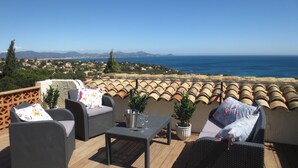 A terrace with wicker furniture, a table, and potted plants. - Luxury villa, heated pool, panoramic sea view, air conditionin (Roquebrune-Sur-Argens)