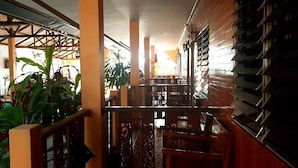 A corridor with a wooden railing, a staircase, and a view of a building with balconies.