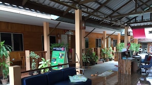 A spacious lobby with a blue sofa, wooden decor, and potted plants.