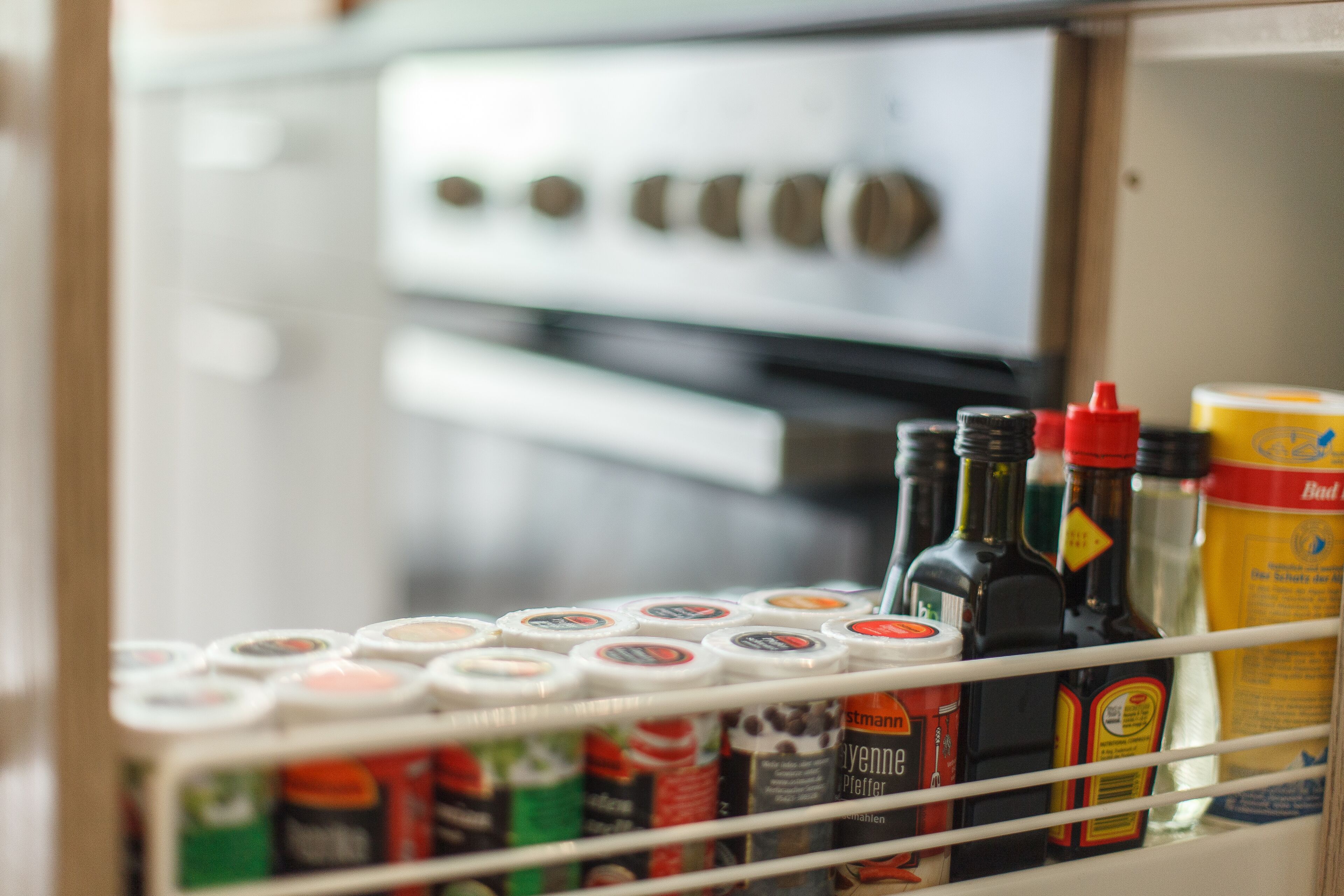 A kitchen area with a variety of condiments and bottles on a shelf.