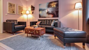 A modern living room with a sofa, ottoman, and a vintage suitcase coffee table.
