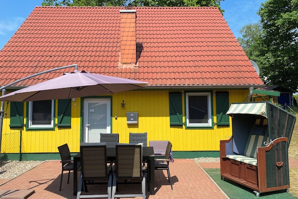 Umzäunter Garten, Terrasse, Sonnenschirm, Sonnenliegen, Strandkorb und Grill.