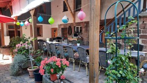 Un espace extérieur aménagé pour les repas, avec des tables et des chaises, des plantes en pot et un escalier.