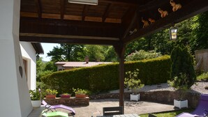 A covered patio area with a wooden table and chairs, surrounded by potted plants and a well-maintained hedge. - Center Alsace, house 2 to 5 pers. Between Colmar and Strasbourg. Exceptional view (Neubois)