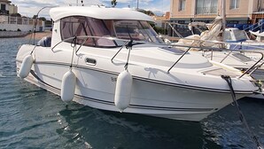 A white motorboat docked at a marina with a building in the background.