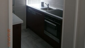 A compact kitchen with a window, a sink, and a stove.