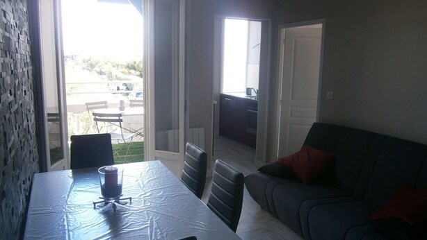 An open-plan living area with a dining table, a sofa, and a view of the outdoor patio.