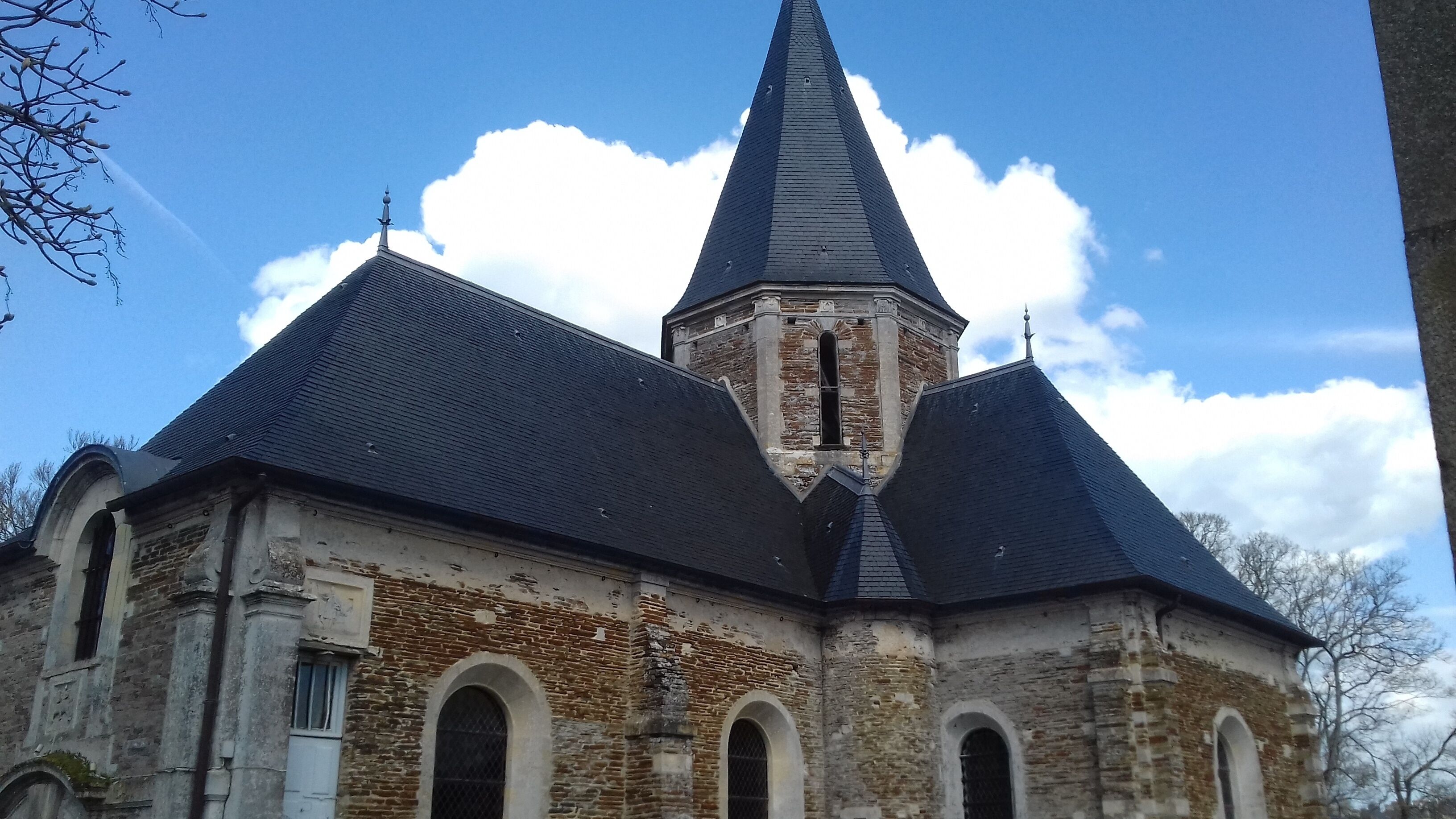 A church with a tall, pointed steeple and a brick facade.