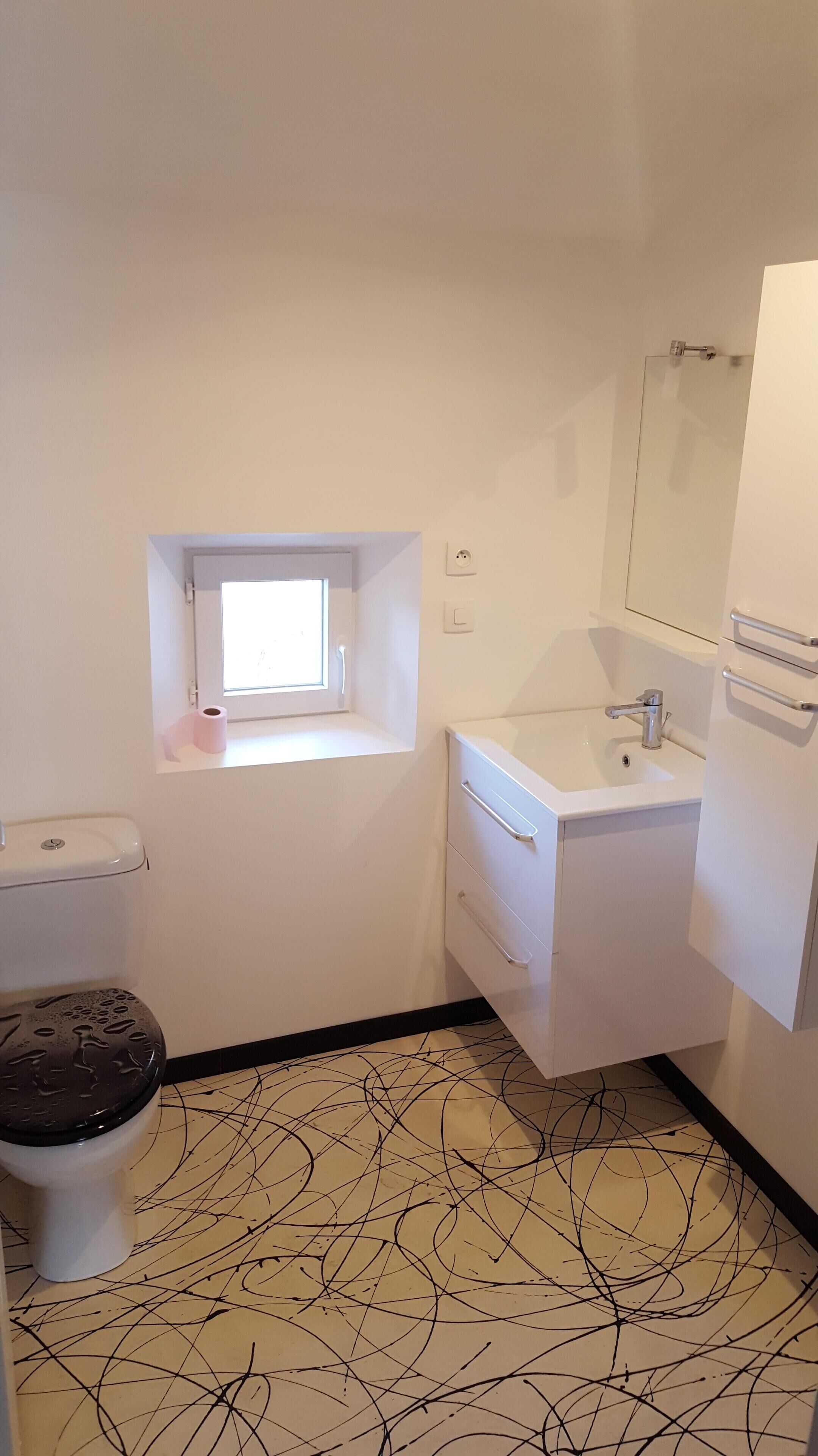 Une petite salle de bain propre, équipée de toilettes, d’un lavabo et d’une fenêtre.