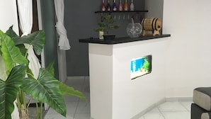 A reception area with a counter, a potted plant, a wine rack, and a framed picture. - Maginifique T2 seasonal rental (SAINT ESPRIT)