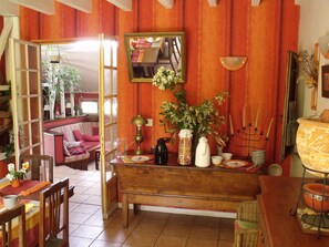Ein gemütlicher Essbereich mit Holztisch, Stühlen und einer Bank. Ein Spiegel ist an der Wand angebracht, und auf dem Tisch befinden sich verschiedene Dekorationsgegenstände.