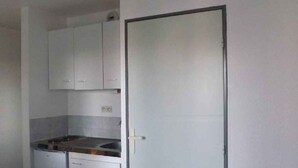 Pieni, käytännöllinen keittiö, jossa on valkoiset kaapit, liesi ja astianpesukone.