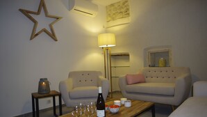 Una sala de estar con dos sofás, una mesa de centro de madera con copas de vino y una botella, una lámpara de pie y una decoración de estrella en la pared.