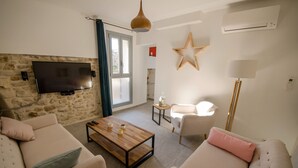 Una sala de estar moderna con una pared de piedra, un televisor de pantalla plana, una mesa de centro de madera y dos sofás.