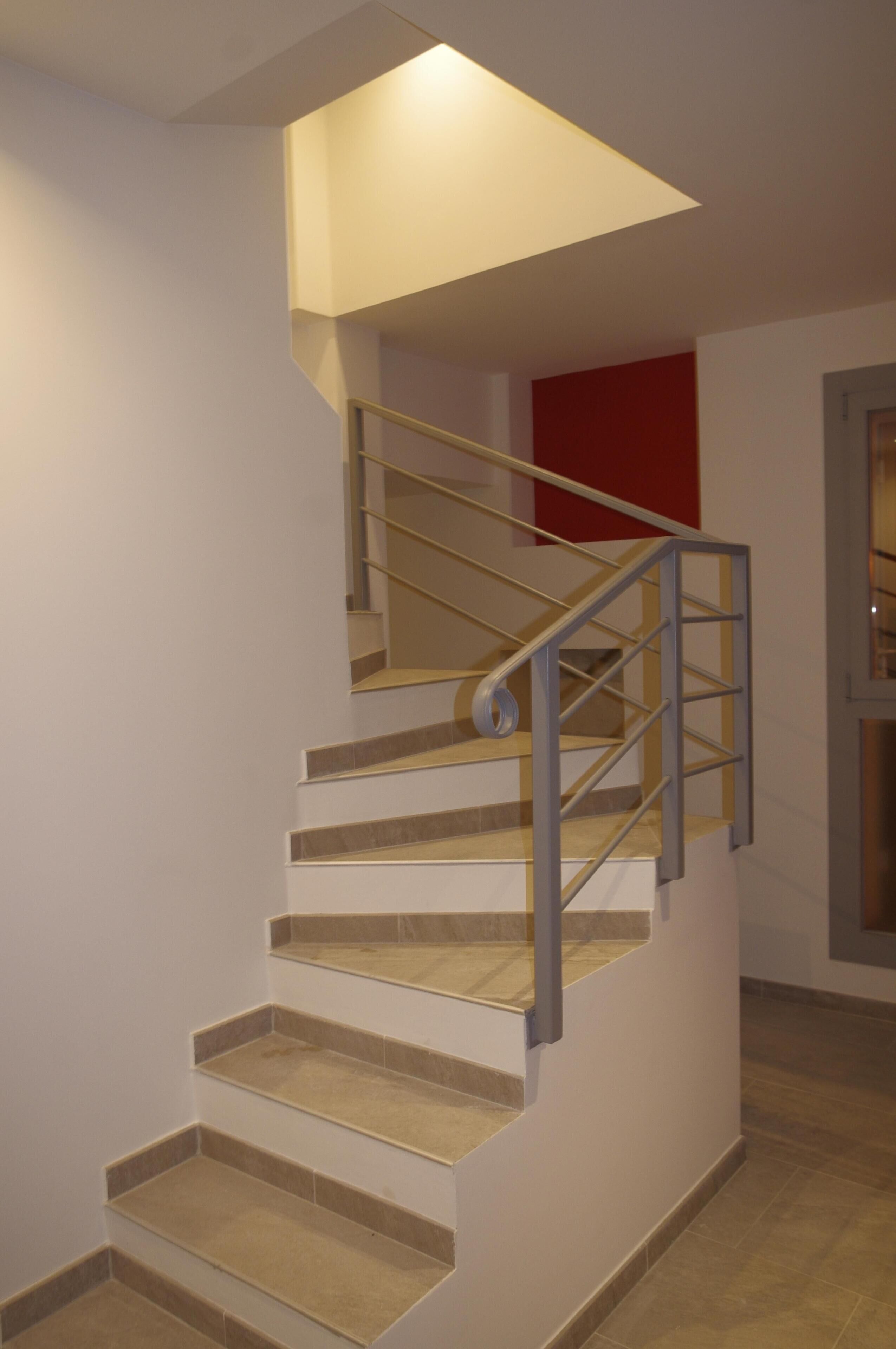 A staircase with a modern design, featuring a metal handrail and wooden steps.