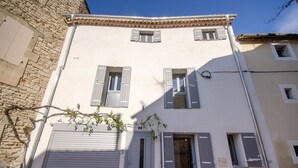Un edificio con fachada de piedra, sección superior blanca y contraventanas en las ventanas.