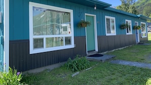 A row of blue cabins with white-framed windows, wooden decks, and hanging flower baskets. - 1 Block from the Bay!  (Seward)