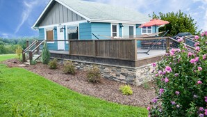 A two-story house with a stone foundation, a covered porch, and a fenced deck.