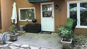 A covered patio area with a grill, a chair, and a potted plant. - Minutes from Everything- Lambeau Field,  Door County and more !, (Hobart)