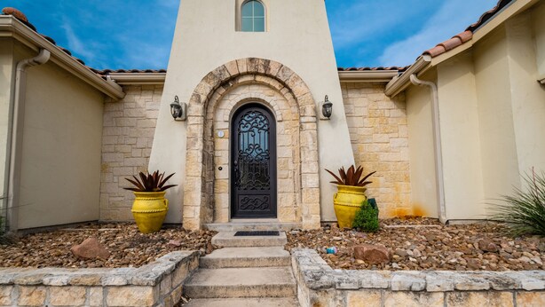 A building with a central arched entrance, stone walls, and a tiled roof.