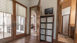 A hallway with wooden flooring, a sliding glass door, a television on a shelf, and storage boxes.