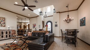 A spacious living room with a sectional sofa, a dining area with a table and chairs, and a kitchen in the background.