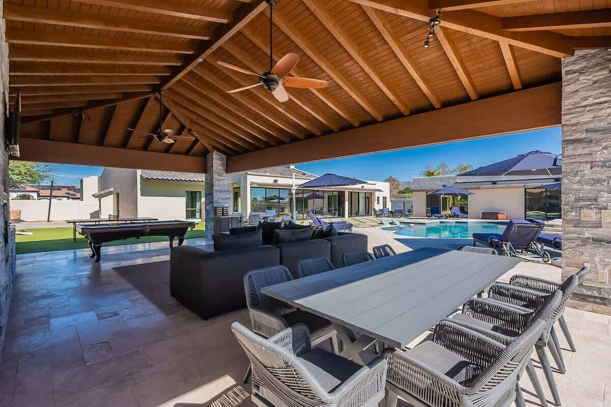 An outdoor patio with a pool table, seating, and a pool.